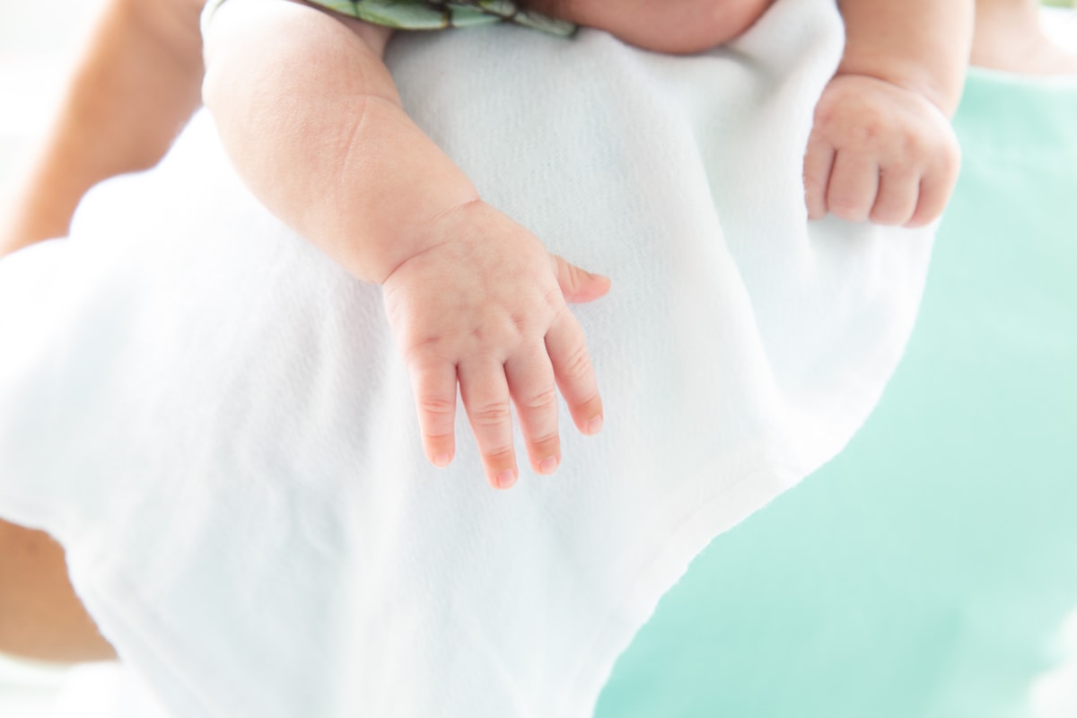 baby sleeping on the shoulder, focusing on the hand related to Soothing Solace: Mint Baby Bedding for a Peaceful Nursery
