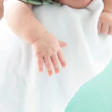 baby sleeping on the shoulder, focusing on the hand related to Soothing Solace: Mint Baby Bedding for a Peaceful Nursery