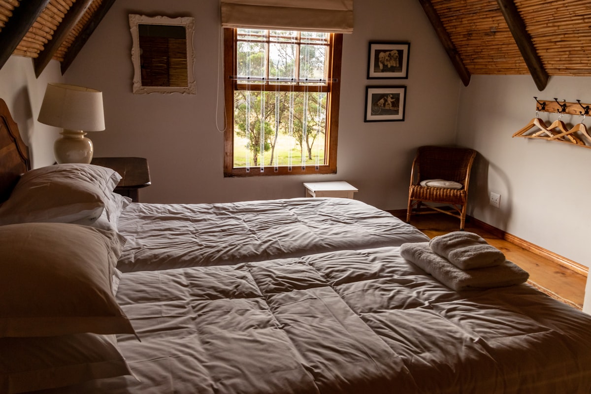 Bedroom in a farm cottage with a bedside lamp on a bedside table related to Unwind in Walla Walla: Bed and Breakfast Bliss Awaits