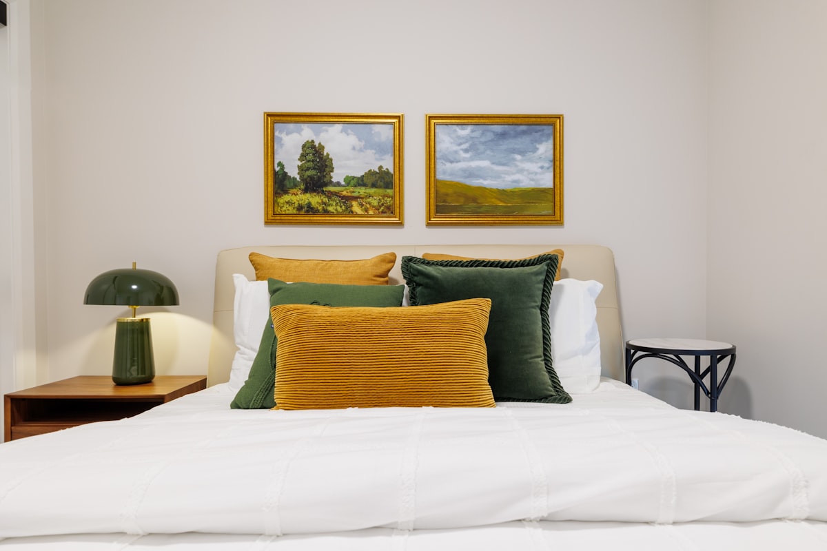 Bedroom with landscape paintings and green lamp. related to The Evolution of Modern Bed Frames