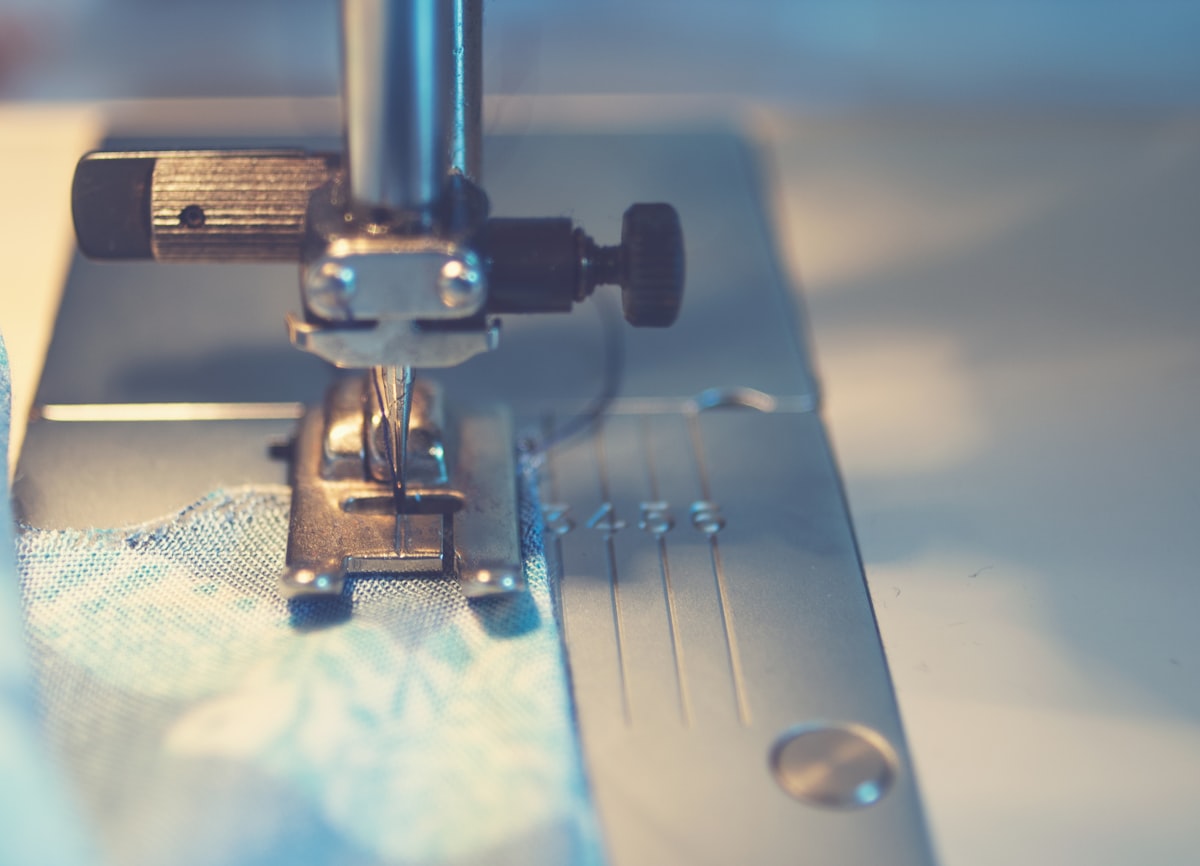 blue textile under a sewing machine needle related to Sew a Beautiful Valance: A Step-by-Step Guide