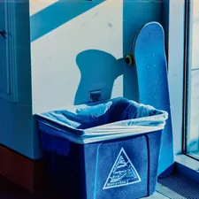 Blue trash can and skateboard by a window related to Choosing the Right Trash Cans for Your Home