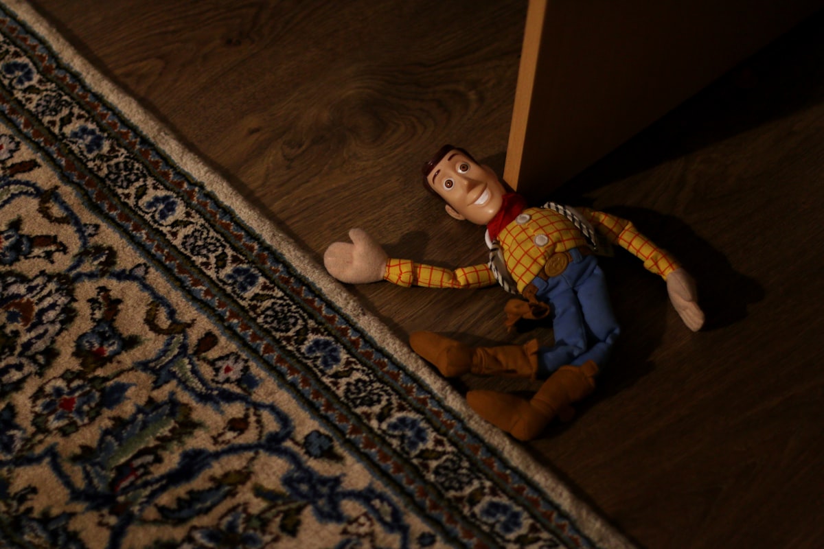 boy in blue and white plaid dress shirt and blue pants sitting on brown wooden floor related to Transform Your Child's Room into a Toy Story Adventure with These Amazing Bed Sets