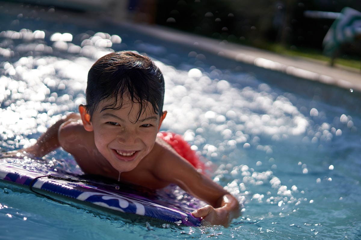 boy in pool smiling during daytime related to Common Issues with Bedwetting in Kids