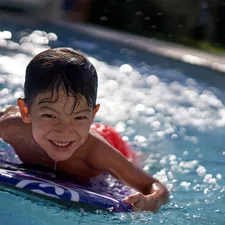 boy in pool smiling during daytime related to Common Issues with Bedwetting in Kids