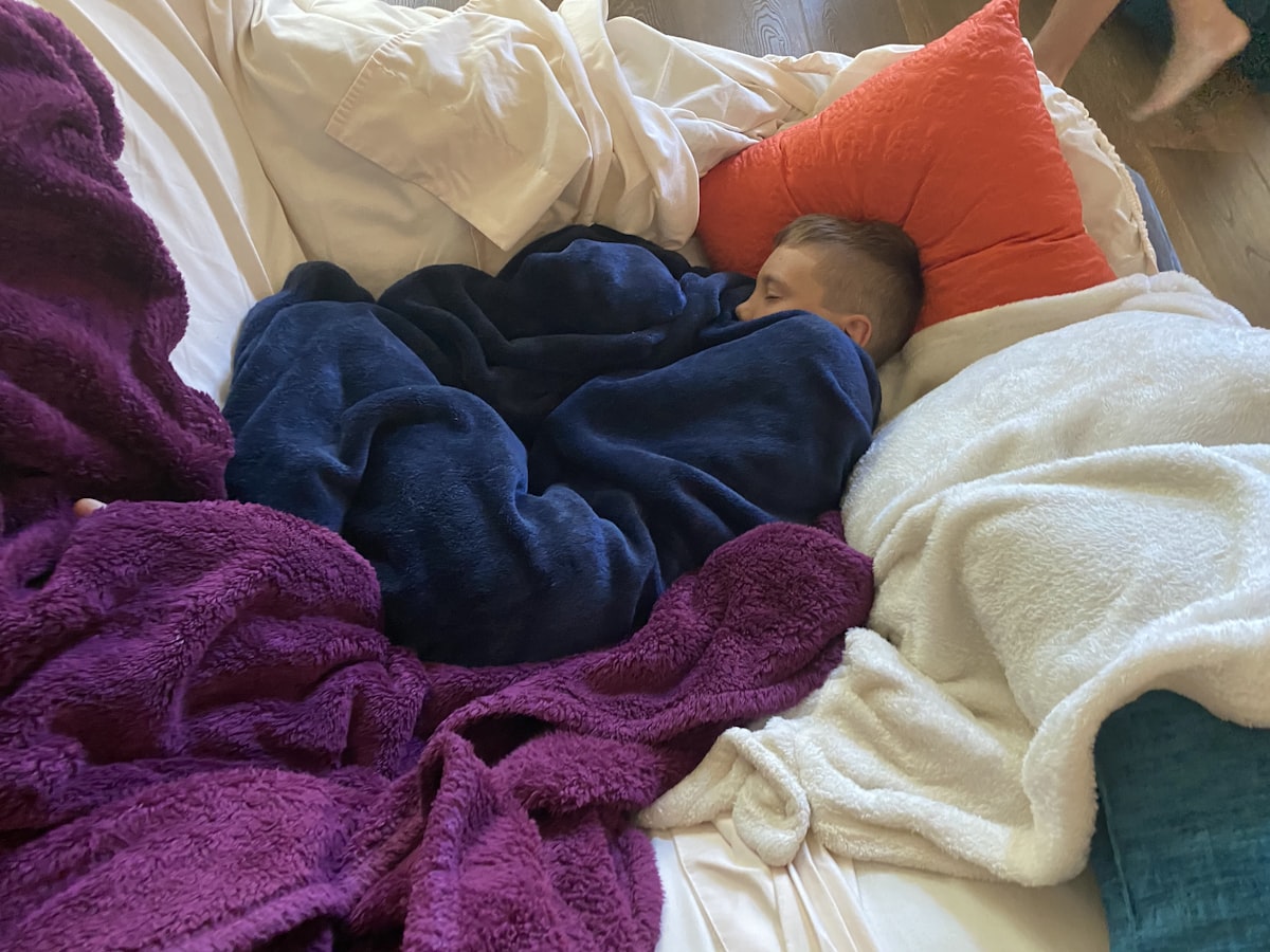 boy sleeping among blankets related to Exploring My Pillow at Bed Bath & Beyond: Comfort Redefined