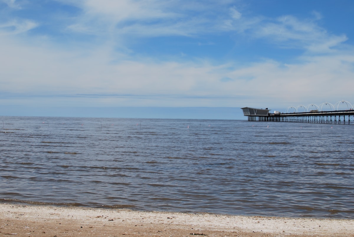 brown wooden dock on sea under blue sky during daytime related to Charming Bed and Breakfast Escapes in Southport, NC