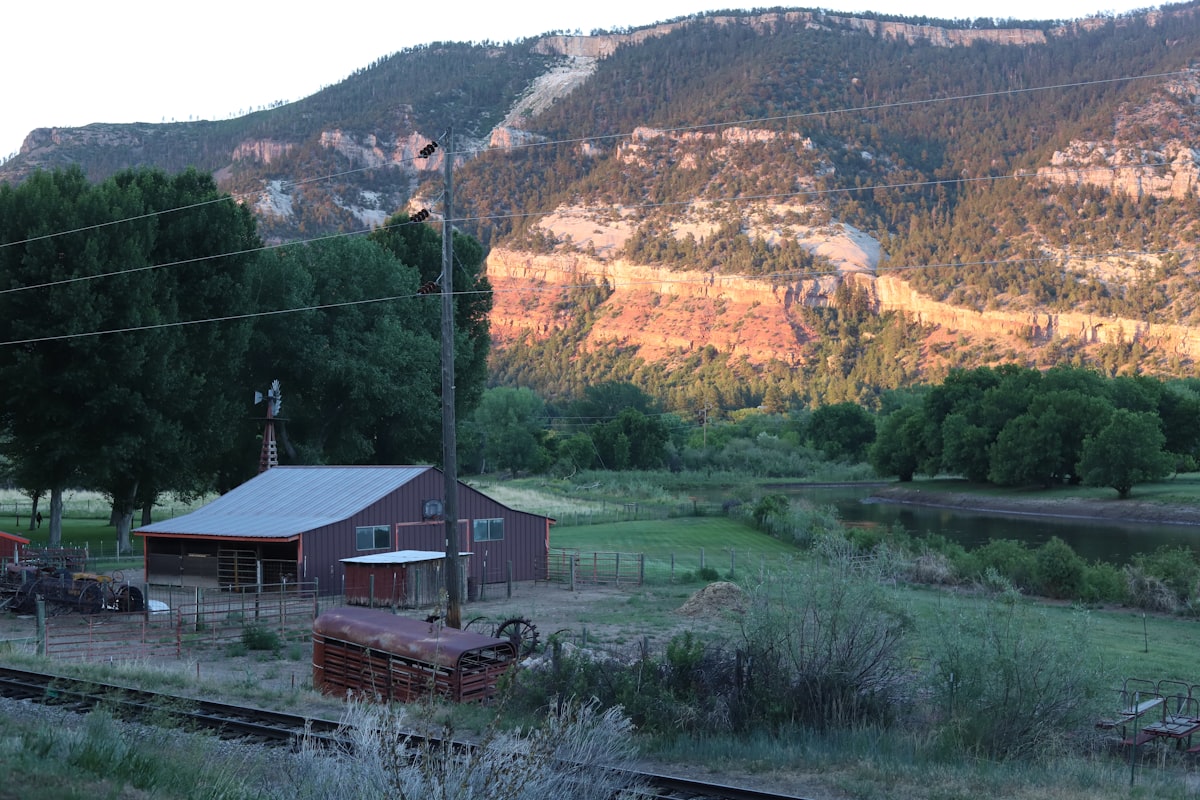 brown wooden house near green grass field and mountain during daytime related to Cozy Getaways in Durango, CO