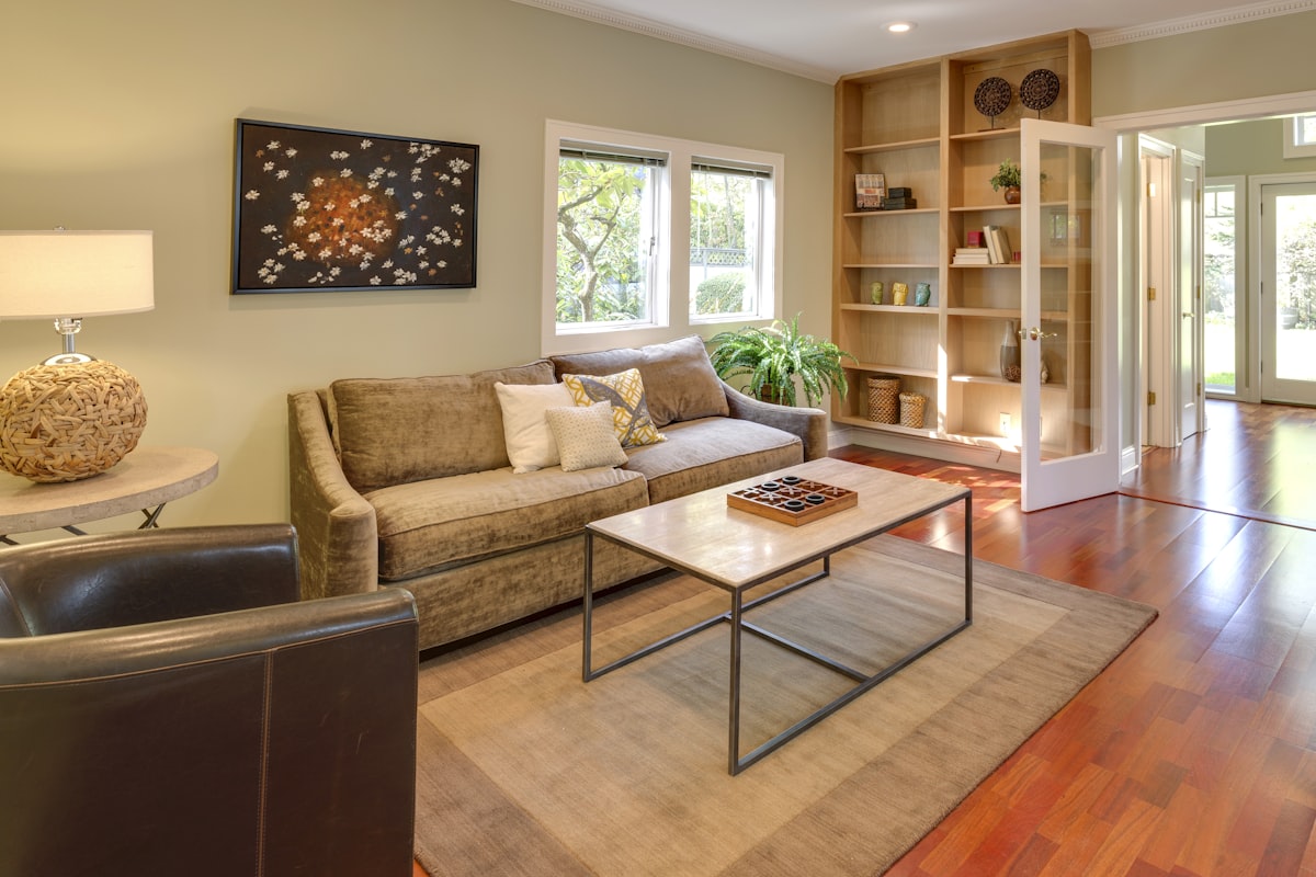 brown wooden table and couch with brown wooden bookshelf related to Enhancing Your Home with Hard Window Valances