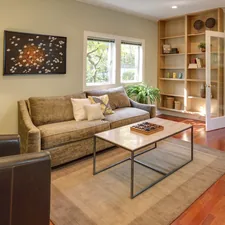 brown wooden table and couch with brown wooden bookshelf related to Enhancing Your Home with Hard Window Valances