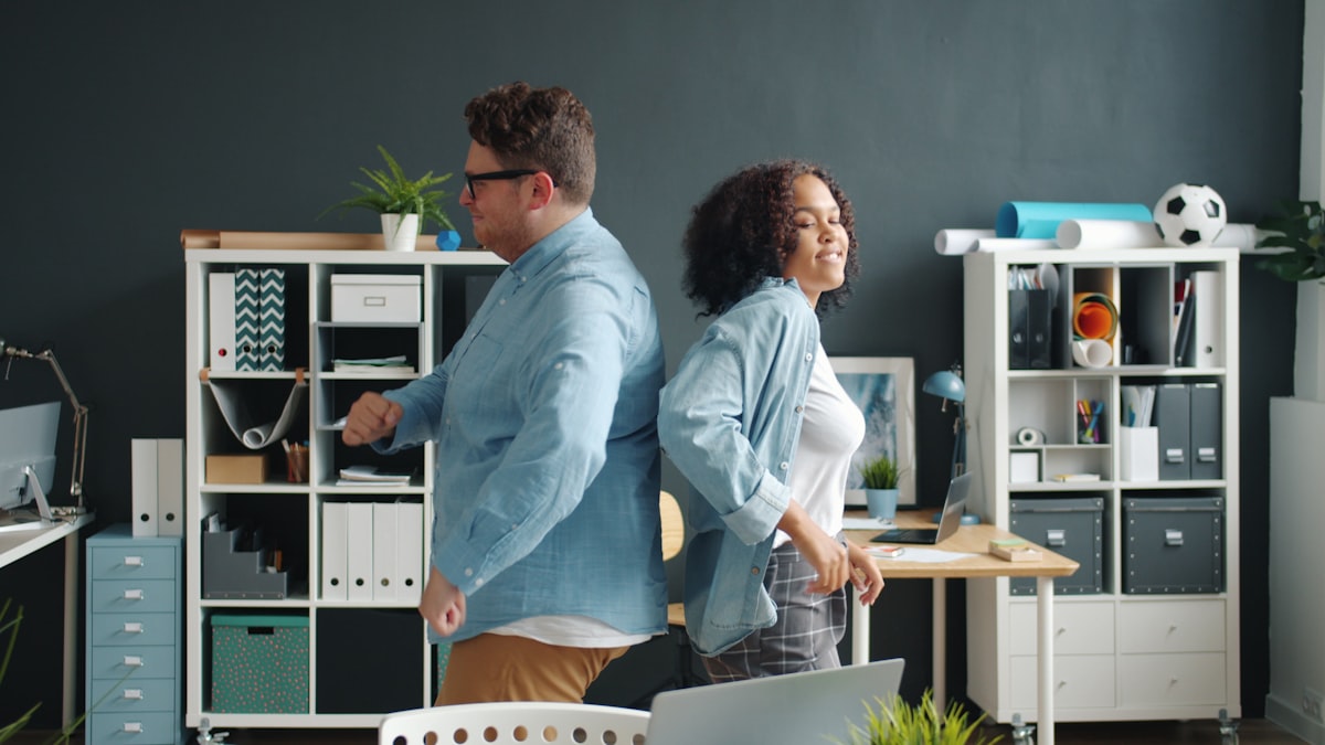 Caucasian man and Afro-American woman coworkers dancing in office, guy is falling being crazy. Happiness, relaxation and business concept. related to Maximizing Your Space with Overstock Bed Frames: A Smart Buy