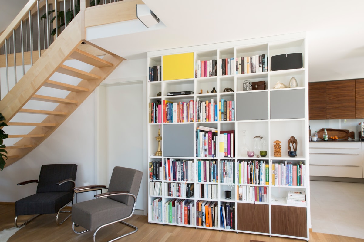 Ceiling-high shelf in a material combination of MDF and solid wood. Used as a bookshelf in a living room. related to Transforming Spaces: The Ultimate Guide to Amazon Kids Beds