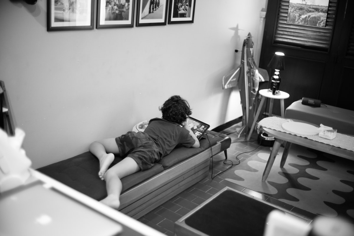 Child lying on a daybed looking at a tablet. related to The Ultimate Space-Saver: Daybed with Pull Out Bed
