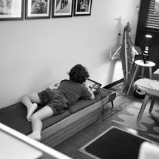 Child lying on a daybed looking at a tablet. related to The Ultimate Space-Saver: Daybed with Pull Out Bed
