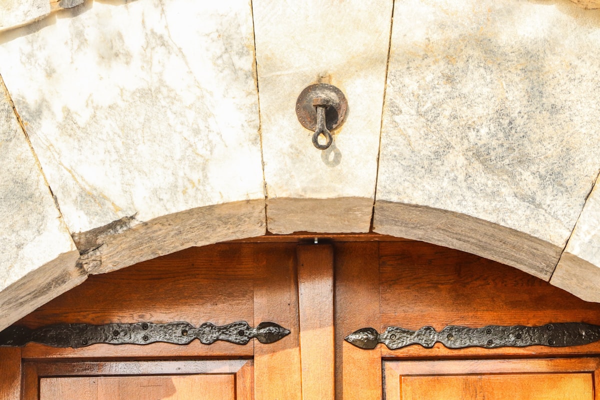 Close-up of an old wooden door with ornate hinges. related to Elegant Entryways: Chandelier Options for a Warm Welcome