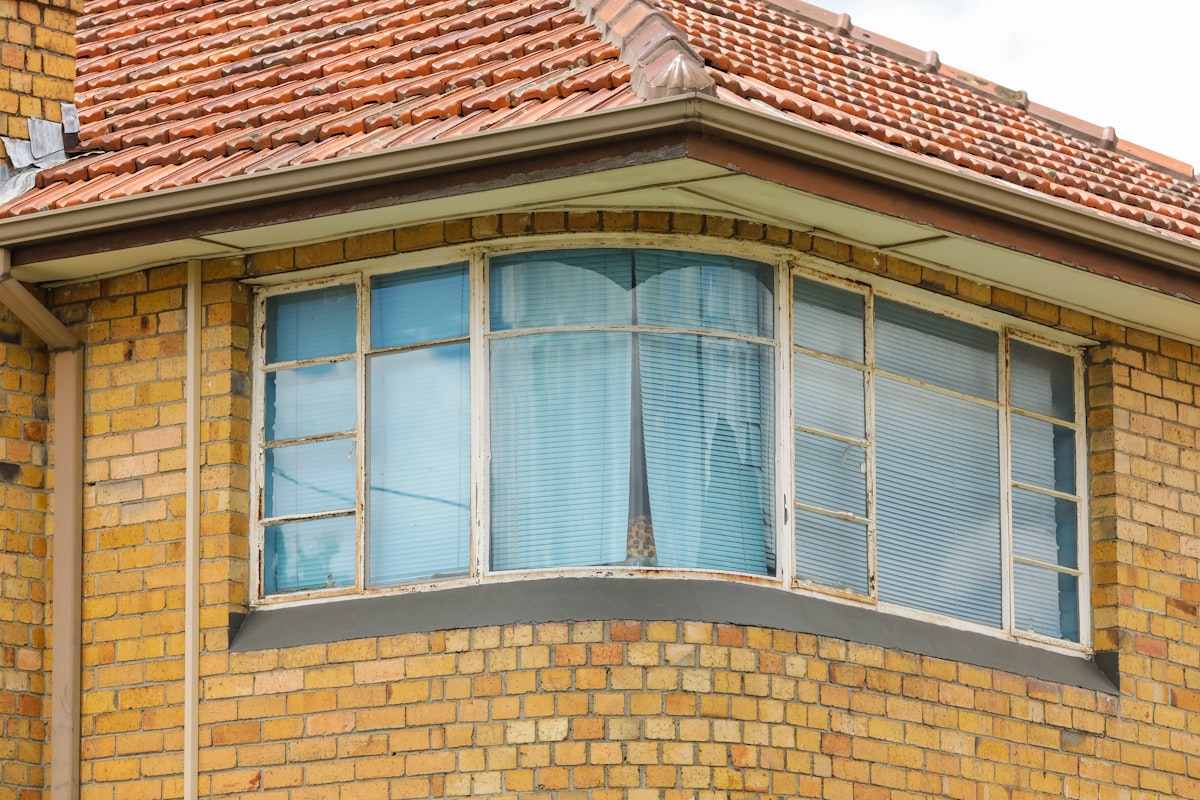 close-up photo of brown concrete house with glass windows during daytime related to Bay Window Valances: Expert Window Treatments for Unparalleled Elegance