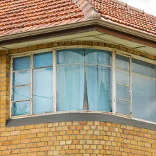 close-up photo of brown concrete house with glass windows during daytime related to Bay Window Valances: Expert Window Treatments for Unparalleled Elegance
