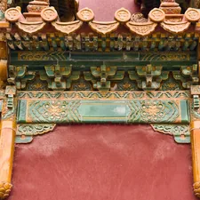Craftsmanship on a traditional building in a historic location with detailed carvings and rich colors outside in the daytime - Visitors can see intricate wooden designs and colorful decorations on a building in a historic area during daylight. The structure shows fine craftsmanship. related to Traditional Elements of a Chinese Wedding Bed