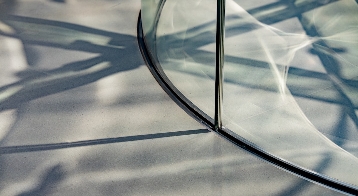 Curved glass reflecting shadows on a textured surface. related to Elegant Entrance: The Perfect Glass Entryway Table for Your Home