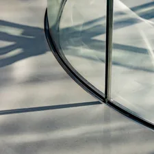 Curved glass reflecting shadows on a textured surface. related to Elegant Entrance: The Perfect Glass Entryway Table for Your Home