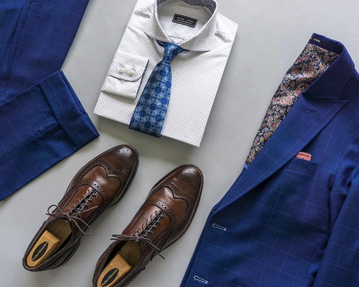 Dapper Professional flatlay featuring a custom suit and a custom shirt with a wide spread collar. A pair of brown leather wingtip dress shoes are pictured as well. related to Transforming First Impressions: Stylish Entryway Closet Ideas
