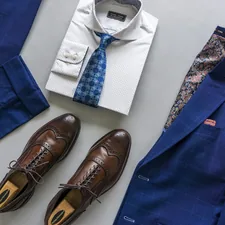 Dapper Professional flatlay featuring a custom suit and a custom shirt with a wide spread collar. A pair of brown leather wingtip dress shoes are pictured as well. related to Transforming First Impressions: Stylish Entryway Closet Ideas