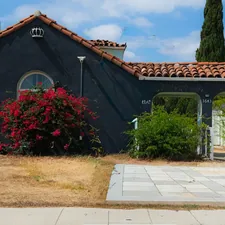 Dark house with red flowers and a carport. related to Elevate Your Home's Curb Appeal: Tips and Ideas for Your Pottery Barn Entryway