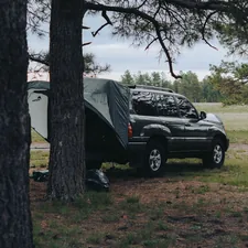 Dark suv and tent camping under trees related to Ultimate Guide to Truck Bed Tents