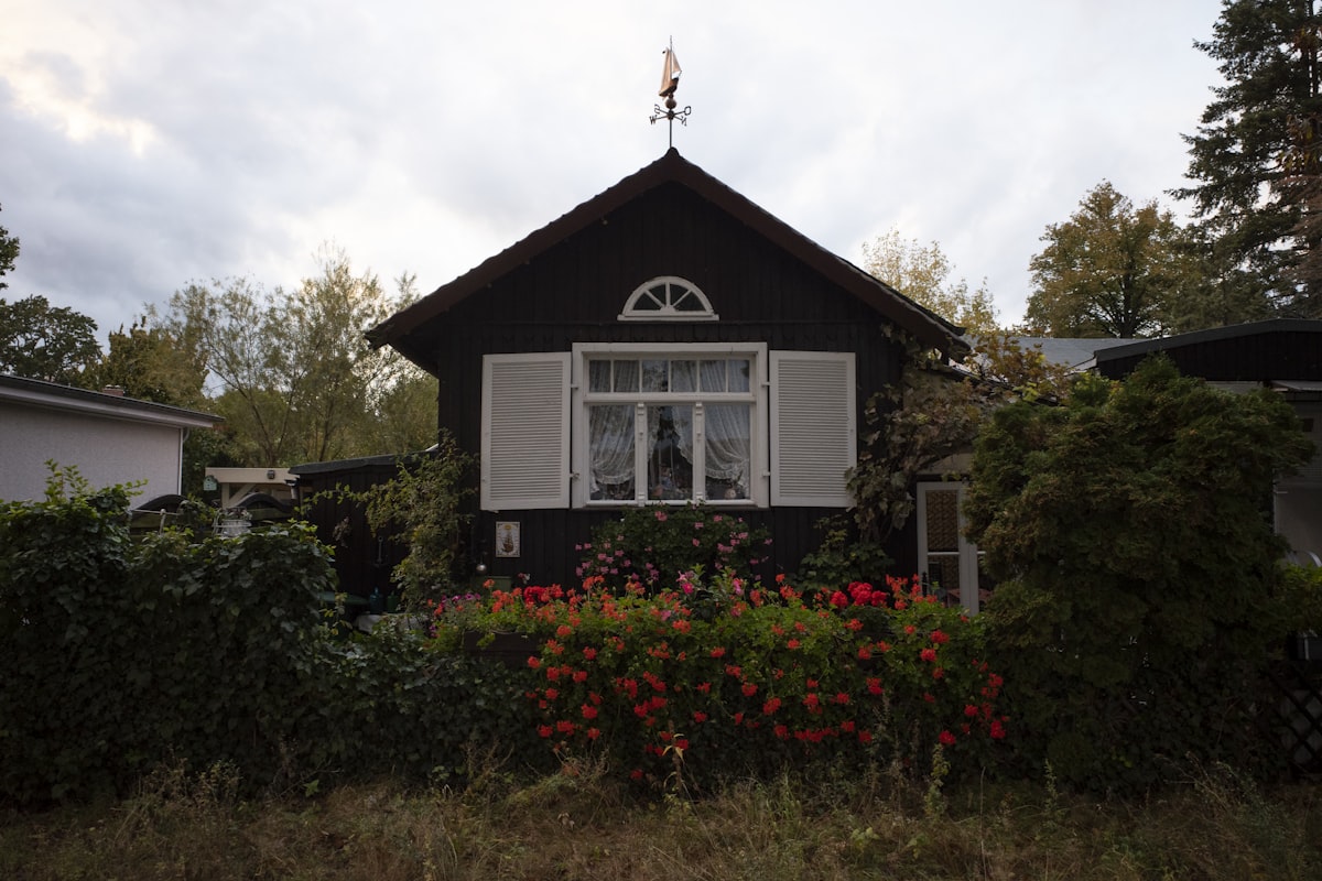Dark wooden house with white shutters and flowers. related to Embrace the Somber Elegance of Dark Wood Beds