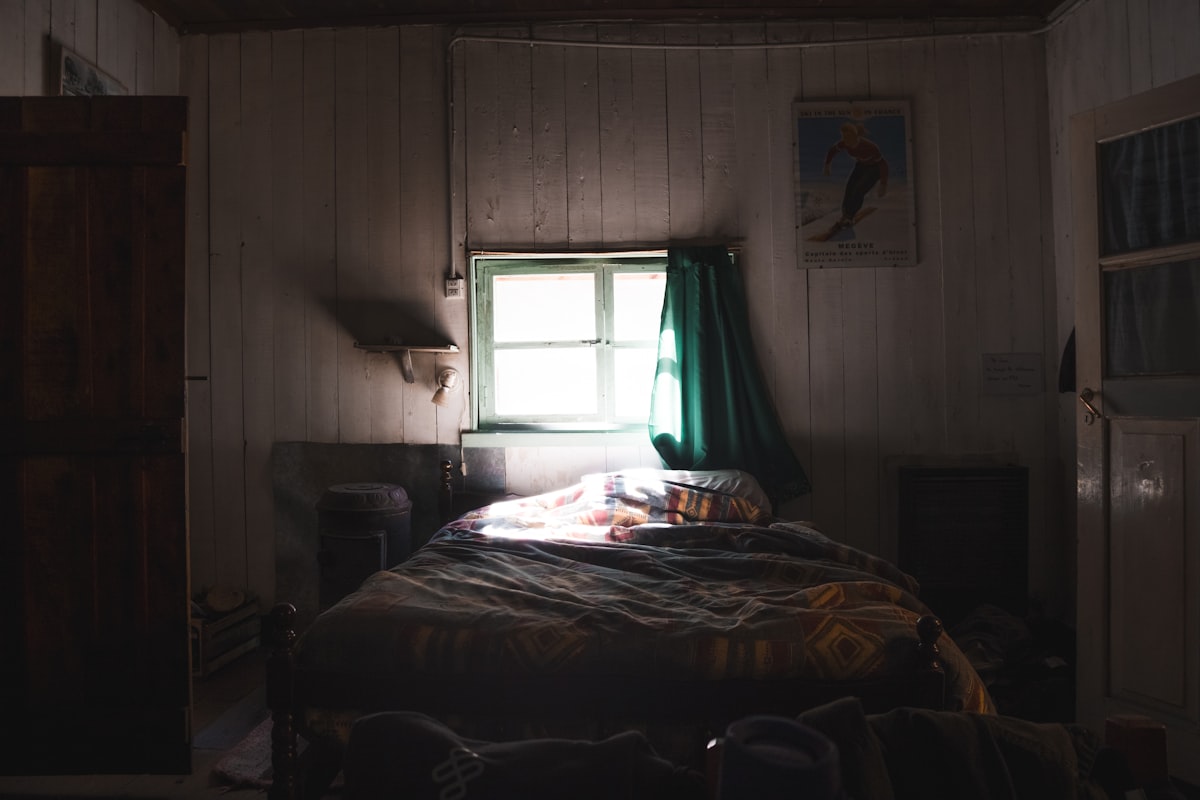 Dimly lit bedroom with a bed and window related to Charming Escapes: Exploring Farm Bed and Breakfasts