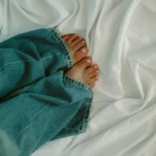 Feet and jeans relax on a soft, white bed. related to Everything You Need to Know About King Bed Size in Feet