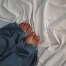 Feet in jeans rest on rumpled white fabric. related to Everything You Need to Know About King Bed Size in Feet