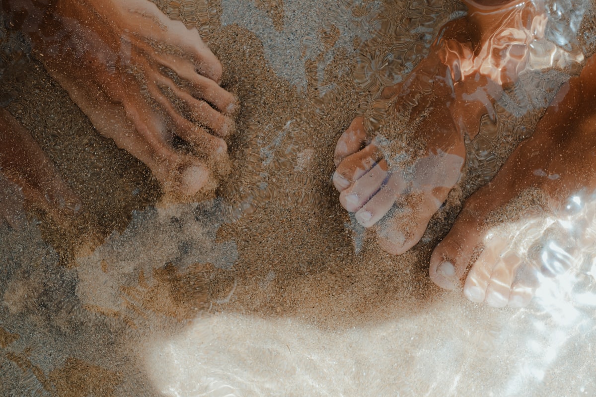 Feet partially submerged in shallow water and sand. related to Exploring Bed Bath & Beyond in Sandy, Utah: Your One-Stop Home Essentials Destination