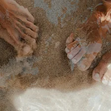 Feet partially submerged in shallow water and sand. related to Exploring Bed Bath & Beyond in Sandy, Utah: Your One-Stop Home Essentials Destination