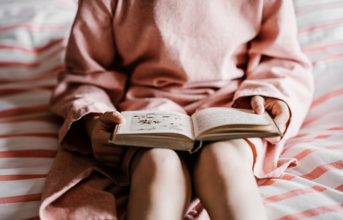 Girl reading a bedtime story book related to The Magic of Bedtime Stories: Timeless Tales for Tucking In