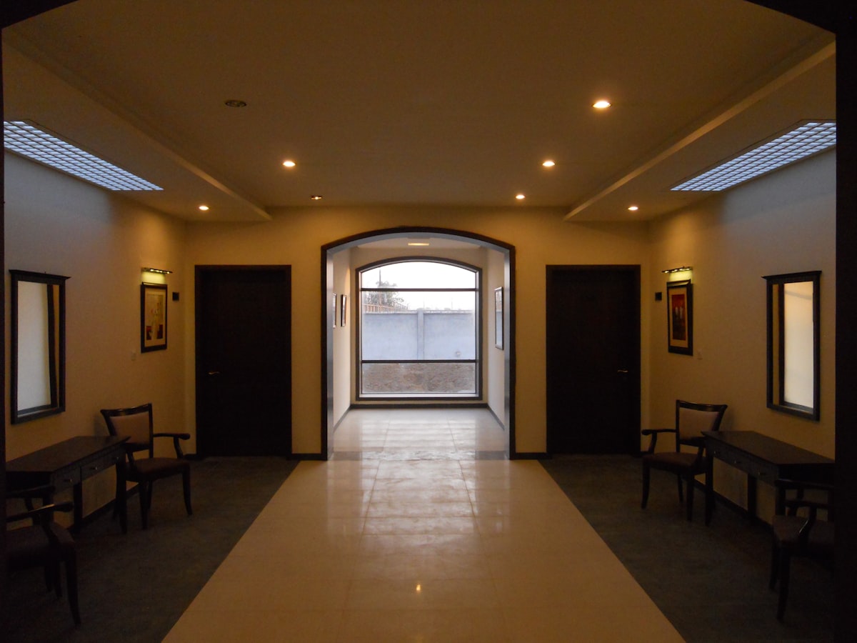Hallway with doors, chairs, and arched window. related to Elevate Your Foyer with an Entryway Hall Tree Bench