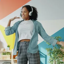 Happy Afro-American student wearing headphones is having fun at home dancing enjoying music indoors relaxing chilling. People and lifestyle concept. related to Transform Your Space: Discovering Curtains at Bed Bath and Beyond