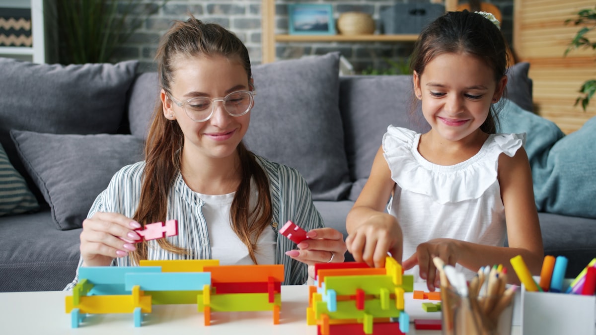 Happy mother and daughter are playing with construction blocks indoors at home holding toys and bonding with each other. Happiness and young family concept. related to Mastering the Art of Building a Twin Bed Frame: A Step-by-Step Guide