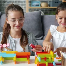Happy mother and daughter are playing with construction blocks indoors at home holding toys and bonding with each other. Happiness and young family concept. related to Mastering the Art of Building a Twin Bed Frame: A Step-by-Step Guide