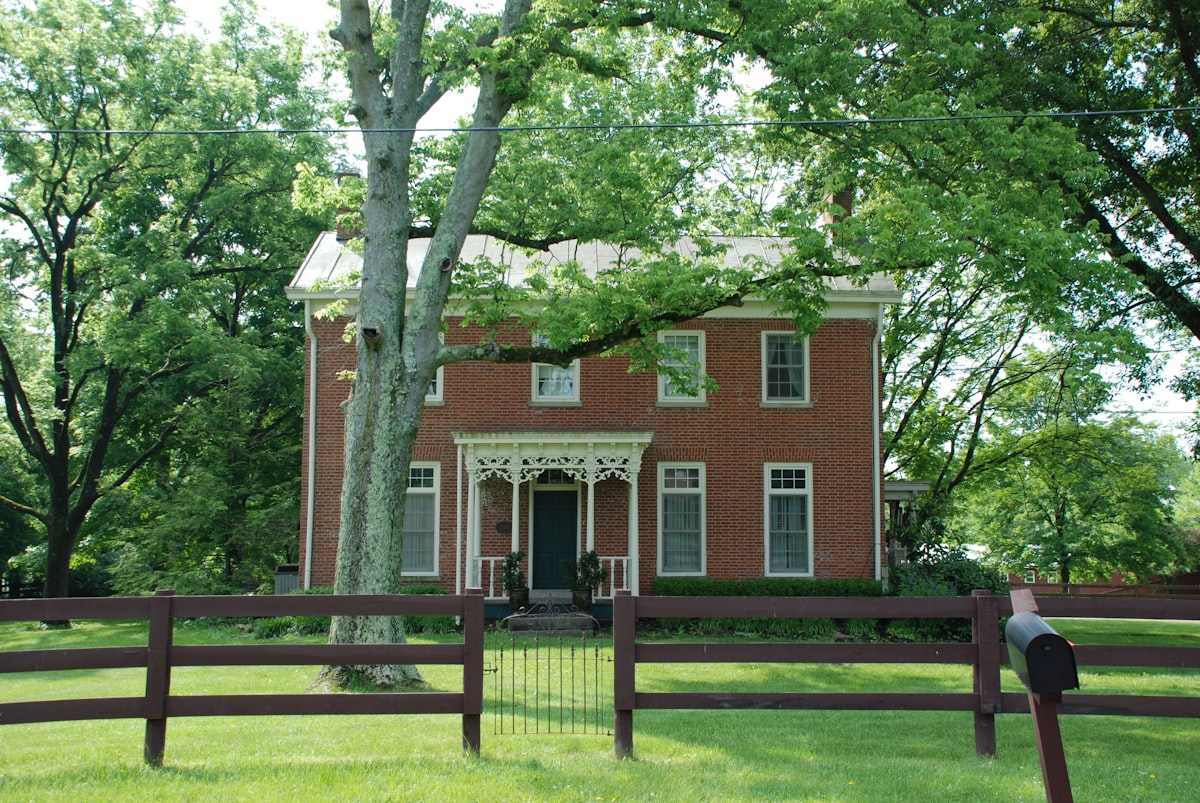 Historic Brick Home with white trim and ornate porch and 3 rail fence related to Discovering the Charm of Bed and Breakfasts in Ohio