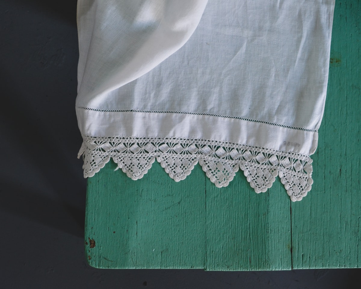 Intricate lace-edged linen on a wooden chair.  related to Shabby Chic Valance: Elegant Window Treatments