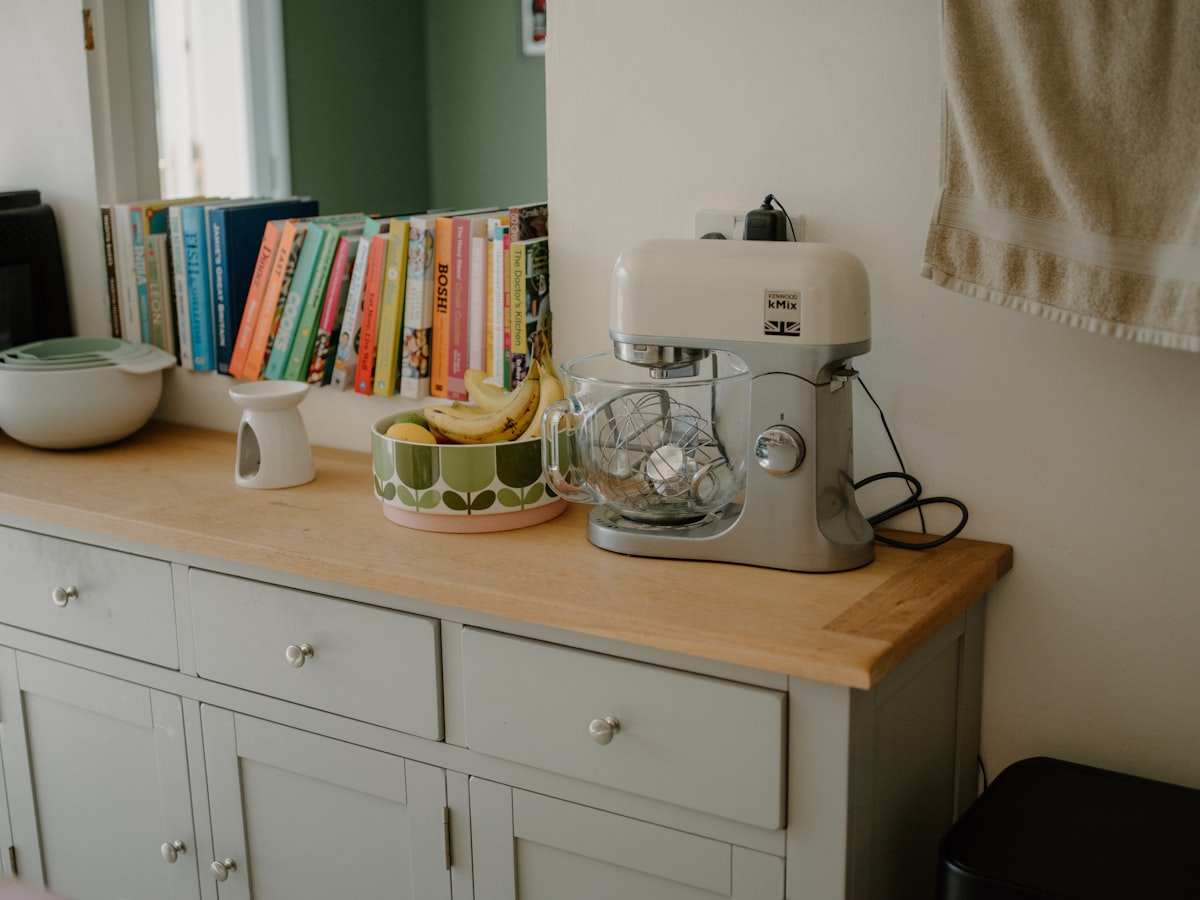 Kitchen counter with mixer, fruit bowl, and books. related to Elevate Your Home Decor with the Grey Oak Sideboard