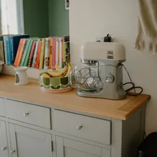 Kitchen counter with mixer, fruit bowl, and books. related to Elevate Your Home Decor with the Grey Oak Sideboard