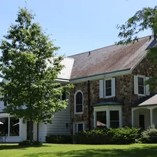Large stone and white house with green lawn and trees. related to Discovering the Charm of Bed and Breakfasts in Ohio