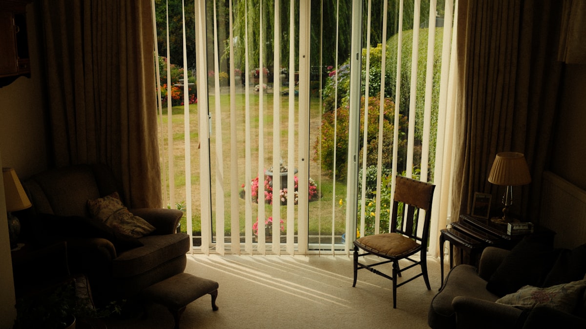 Living room with vertical blinds and garden view related to Vertical Blinds Valance Clips