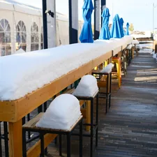 Long outdoor bar covered in snow with blue umbrellas. related to Warm Up Your Outdoor Space with a Majestic Ceramic Fireplace Chiminea