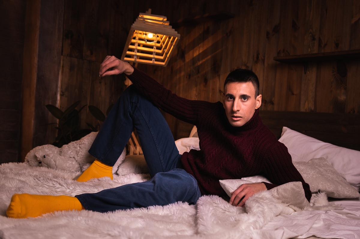 man in black sweater and blue denim jeans sitting on white fur textile related to Exploring the Lives of Jewish Men at Home