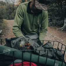 man in green jacket sitting on green plastic chair related to The Ultimate Hunting Bed Sets Guide