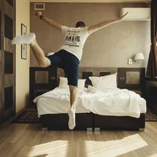 man wearing white shirt about to jump on bed related to Stylish Bedding Ideas for Teen Boys