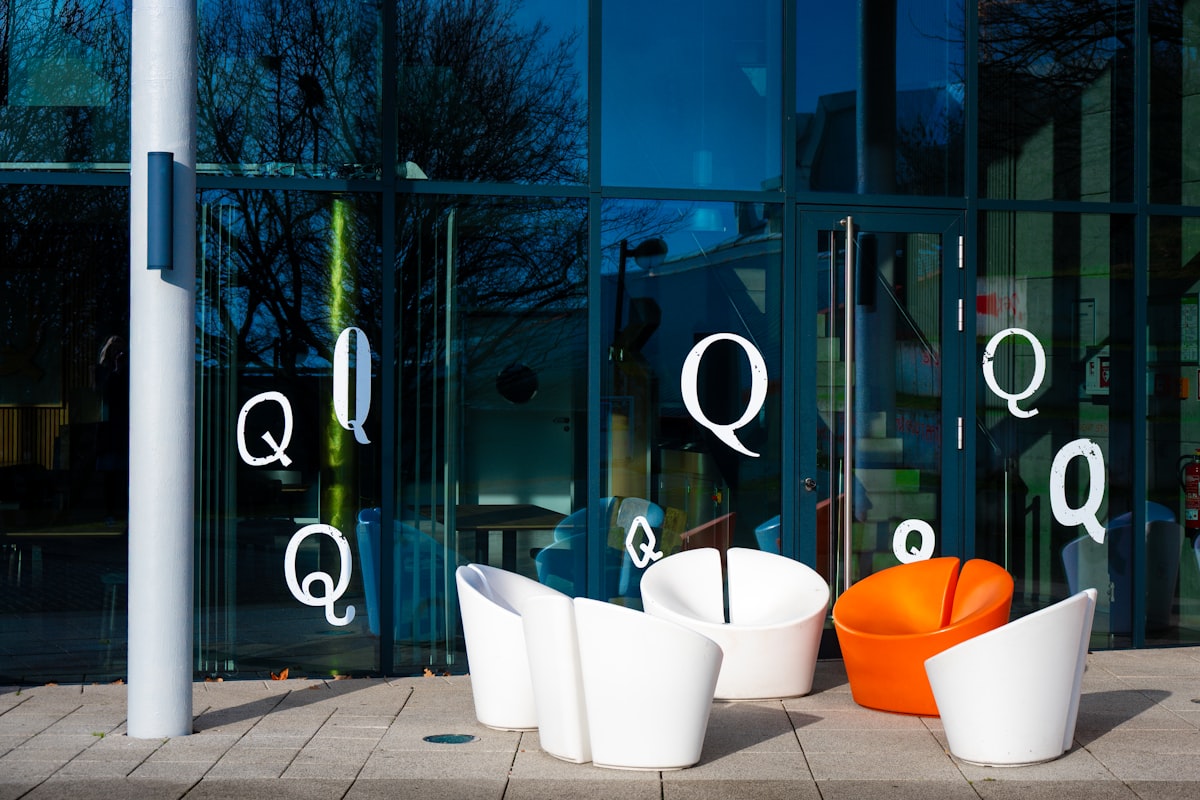Modern chairs outside a glass building with letter q related to Transform Your Home with Modern Entryway Furniture